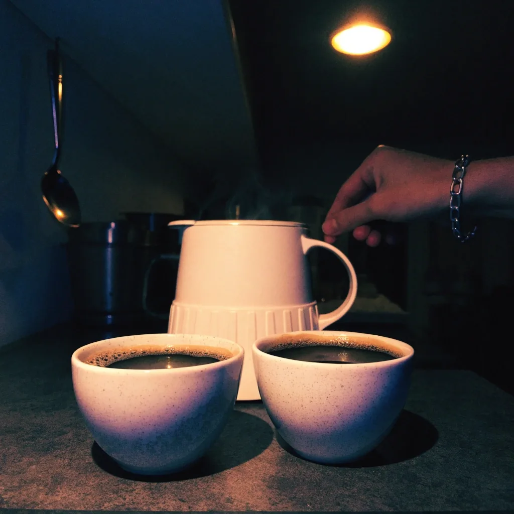 Dos tazas de café filtrado servidas junto a la cafetera compacta