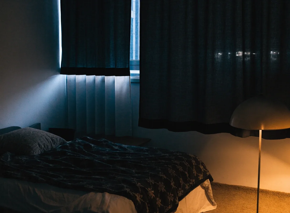 Borde inferior de una cortina roller blackout a medio bajar con luz de ventana detrás