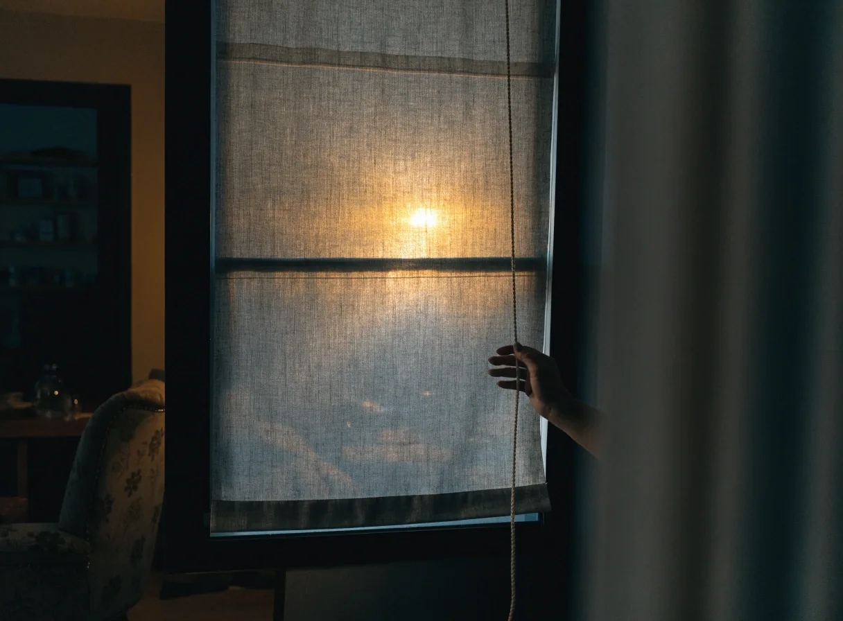 Cortina roller semitransparente bajada sobre un marco de ventana oscuro